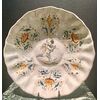 Piatto-crespina in maiolica baccellata a decoro compendiario con putto e motivi vegetali stilizzati.Bottega Vicchi.Faenza.