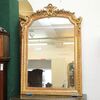 Specchiera in legno dorato con cimasa con strumenti musicali e nastro sul perimetro della cornice