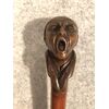 Bastone con pomolo in legno raffigurante figura maschile urlante.