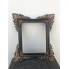 Carved and ebonized wooden frame with rocaille brass details at the corners.     