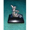 Silver mermaid figure with a forked tail holding a shell. Ebony base.     
