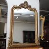 Gilded and carved wooden mirror with mid-19th century scroll crest.