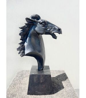 Scultura in bronzo con base raffigurante testa di cavallo.