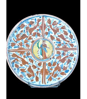 Alzata in maiolica a decoro calligrafico-naturalistico con al centro figura di Santa Caterina d’Alessandria che regge una palma, una spada e un libro.Deruta
