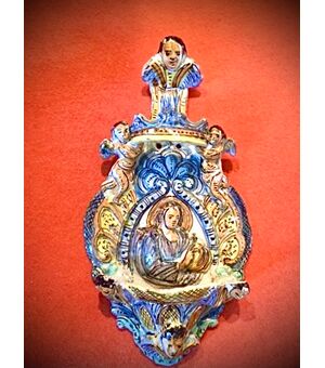 Holy water stoup in majolica with cherubs and figure of a saint in the center.Ariano Irpino manufacture.Campania.     
