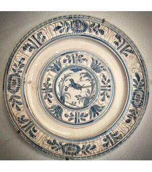 Grande piatto baccellato in monocromia turchina con decori floreali stilizzati e figura di uccello nell’umbone.Manifattura di Pavia.