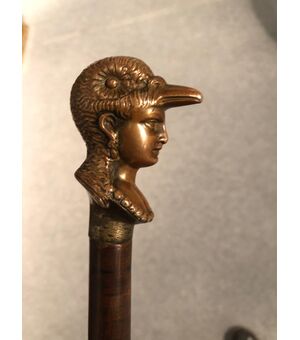 Defense stick with solid bronze pommel depicting a female head with a bird-shaped helmet.     