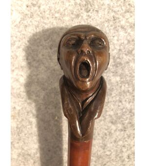 Bastone con pomolo in legno raffigurante figura maschile urlante.