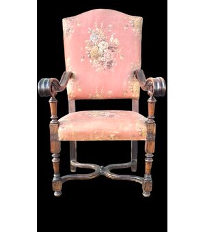 Poltrona in noce con braccioli a volute e gambe tornite.