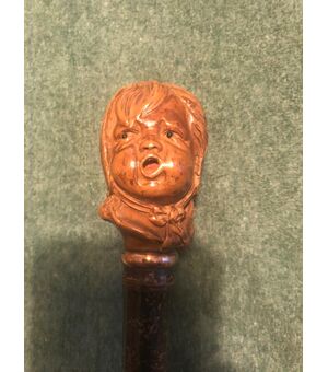 Bastone con pomolo in legno raffigurante testa di bambino che piange.