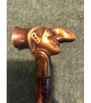 Defense stick with bronze knob depicting the head of a grotesque male figure.     