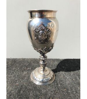 Coppa in argento sbalzato con motivi vegetali stilizzati e scudo con stemma nobiliare.