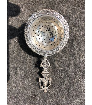 Colino in argento decorato con personaggio popolare e motivi vegetali stilizzati.Olanda.