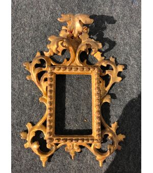 Carved and gilded wooden foil frame with stylized plant motifs.     