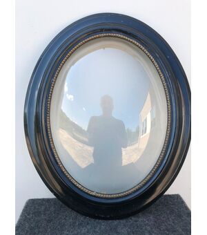 Frame in carved and ebonized wood with convex glass.     