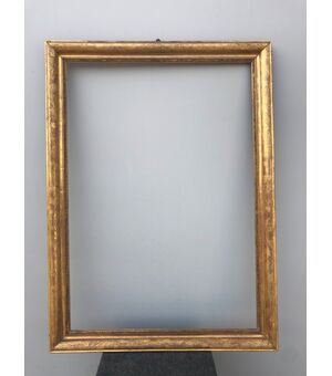 Frame in carved wood and gold leaf with engraved plant motifs.     