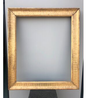 Frame in carved wood and gold leaf with engraved geometric motifs.     