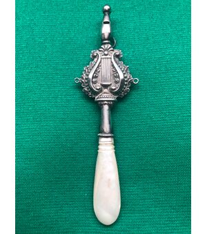 Baby rattle in silver with stylized plant motifs and lyre. Mother of pearl handle.     