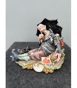 Scultura in porcellana policroma raffigurante personaggio caricaturale con ombrello e cibarie.Giuseppe Cappe’