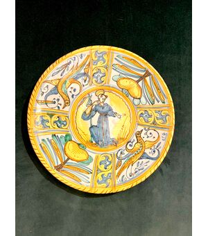 Majolica platter-cutting board decorated with Raphaelesque neighborhoods, stylized plant motifs and rocaille. Central round with figure of Saint. Deruta manufacture.     