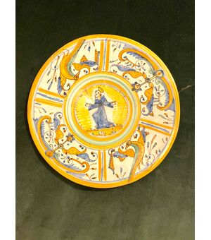 Piatto-tagliere in maiolica con decoro a quartieri a raffaellesche  e tondo centrale con figura di Santo.Manifattura di Deruta.