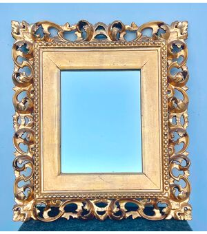 Mirror-frame in wood carved in foil and gold leaf. Florence.     