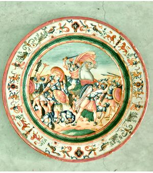 Piatto in maiolica decorato con scena di battaglia nel cavetto e motivi a raffaellesche sulla tesa .Manifattura di Oreste Ruggeri,Pesaro.