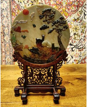 Disco in giada  arricchito con decorazioni di varie pietre all’interno. Provenienza Cina, epoca XX secolo.  Il supporto è in legno patinato ( diametro 30 cm ). 