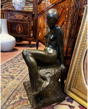 Bronzo nudo femminile di Audagna Virgilio (1903).  La donna è rappresentata seduta su una roccia che funge da basamento alla scultura. Le braccia sono distese, il busto è disposto frontalmente. Il volto è rappresentato di profilo con i capelli raccol