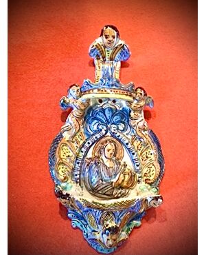 Holy water stoup in majolica with cherubs and figure of a saint in the center.Ariano Irpino manufacture.Campania.     