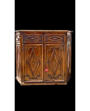 Credenza a sezione esagonale con due sportelli in legno di castagno e motivi geometrici.