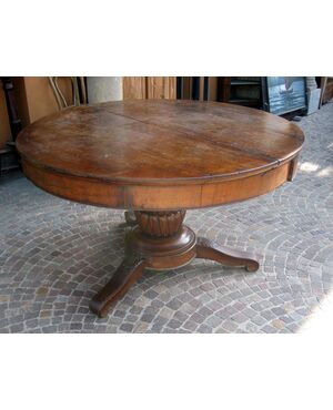Large round table in walnut with a central leg     