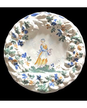 Piatto in maiolica con tesa a fiori in rilievo  e decoro con figura femminile con versatoio. Baldassarre Caravaggio.Pavia.