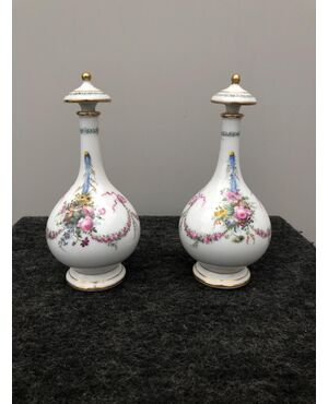Coppia di flaconi portaprofumo in porcellana decorata a fiori e trofei. Francia.