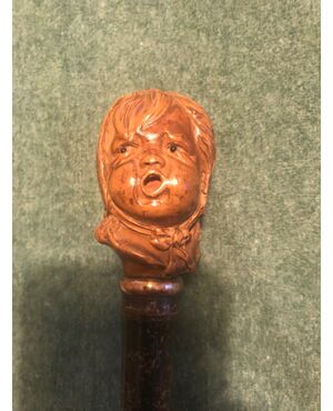 Stick with wooden knob depicting a crying baby&#39;s head.     