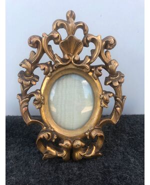 Small foil frame in carved and gilded wood with plant decorations and two doves.     