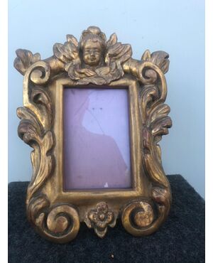Carved and gilded wooden frame with rocaille and putto motifs.     