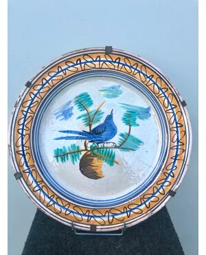 Majolica plate decorated with a bird in the cable and geometric motifs on the brim. Vietri manufacture     