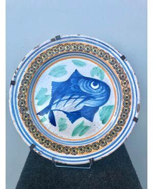 Piatto in maiolica decorato con un pesce nel cavetto e motivi geometrici sulla tesa.Manifattura di Vietri