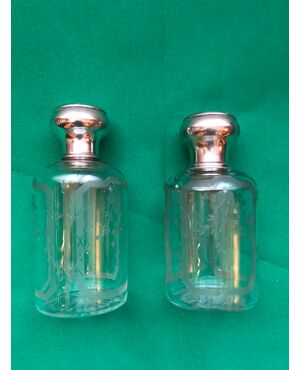 Pair of crystal perfume bottles engraved with floral motifs and silver caps.France.     