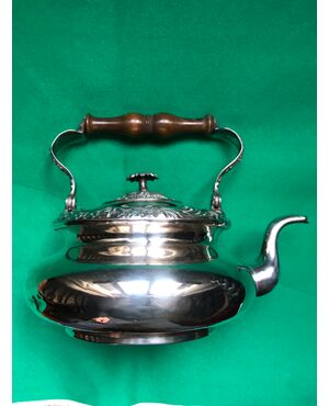 Silver-plated copper teapot with stylized plant motifs and wooden handle.     
