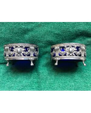 Pair of silver salt cellars with rocaille decorations, cherubs and shields. France.     