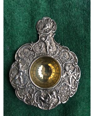 Silver tea strainer with 4 cherubs, birds, floral and rocaille motifs.     