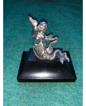 Silver mermaid figure with a forked tail holding a shell. Ebony base.     