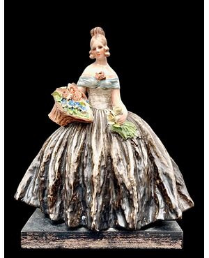 Figura femminile con cesto di fiori.Manifattura di Guido Cacciapuoti.Milano.