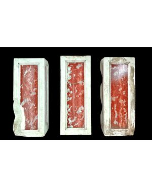 Three architectural elements in marble with a white frame and a variegated red central section.
