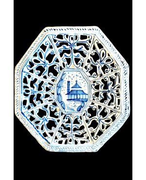 Octagonal raised plate in pierced majolica with geometric motifs and architectural scene in the center. Savona.
