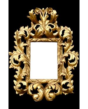 Carved and gilded wooden frame-mirror with 'cartoccio' decoration.