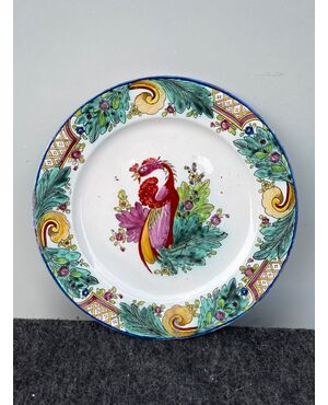 Majolica plate with oriental style decoration with tobacco leaves and rocaille motifs on the brim and bird in the wire.Manufactured by Felice Clerici.Milan.     