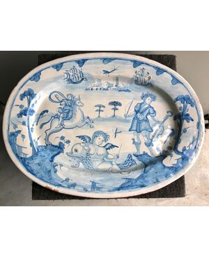 Large oval plate in blue monochrome majolica decorated with characters, architectures, mythological figures and plant motifs.Manufacture of Deruta.Master of the Regiment.     